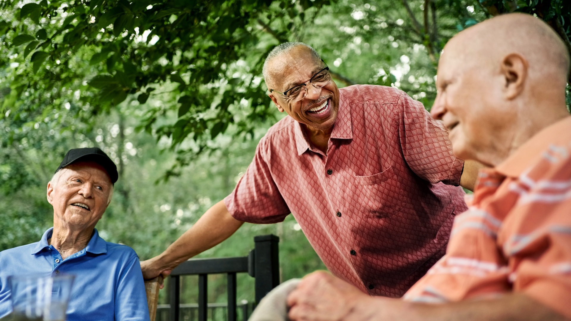 Group of happy seniors talking in backyard area of a home
